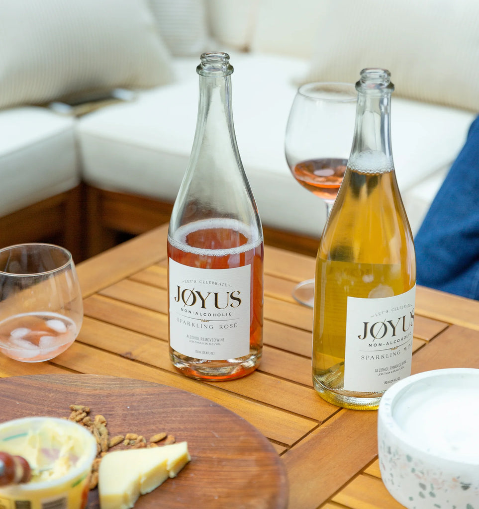 two bottles of Jøyus non-alcoholic wine sitting on a table with cheese